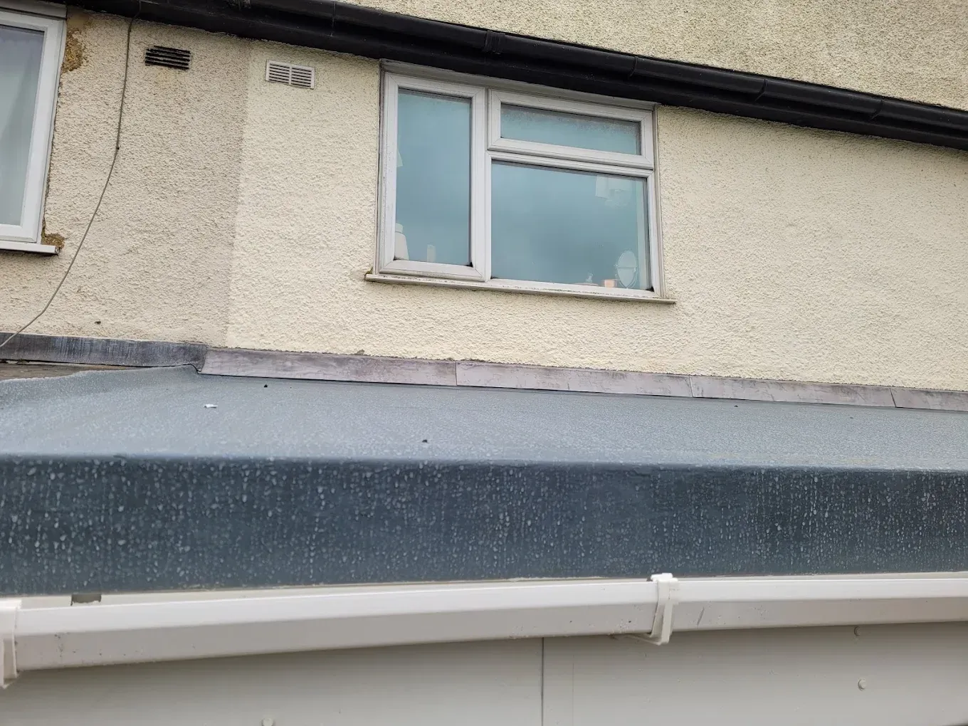 Flat roof and white guttering on house.