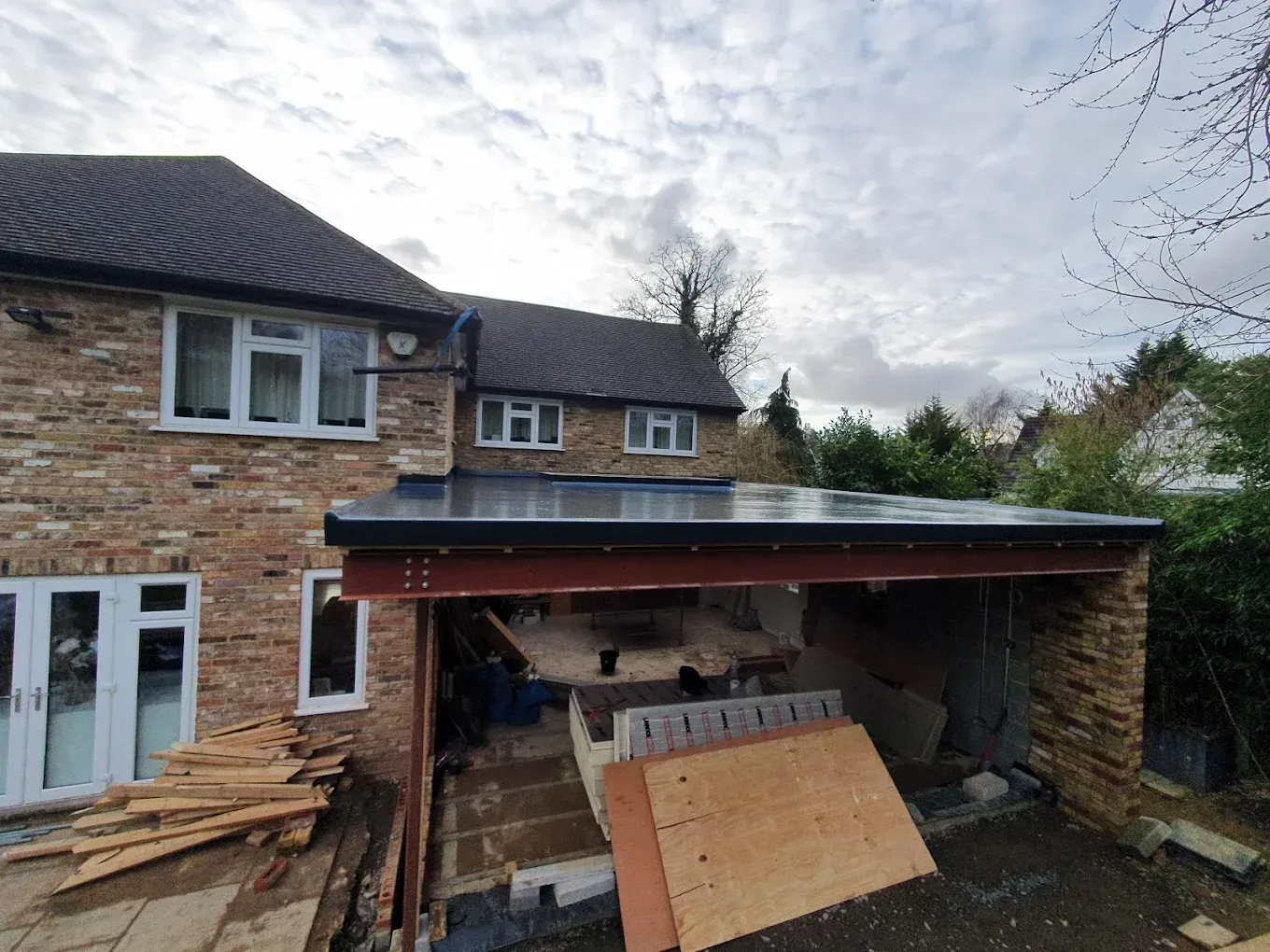 Newly installed flat roof on a house extension in Oxfordshire, showing steel supports and building materials.